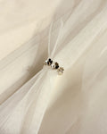 A pair of small silver-toned ring with dainty wildflowers resting on draped white tulle fabric.